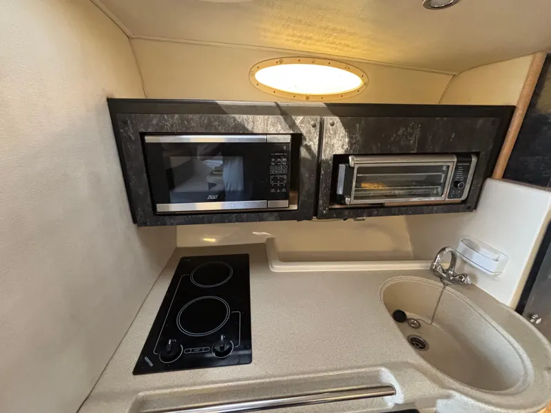 Slide: The Image of 1998 Wellcraft 3000 Martinique kitchen with microwave, stove, and sink. - 9