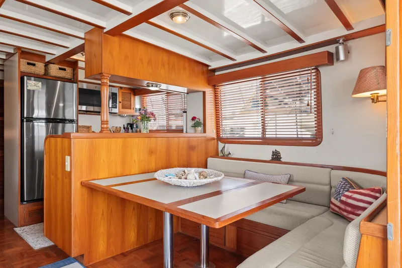 Slide: The Image of Cozy 1996 Kadey-Krogen 48 Whaleback interior with dining area and kitchen, featuring wood accents. - 21