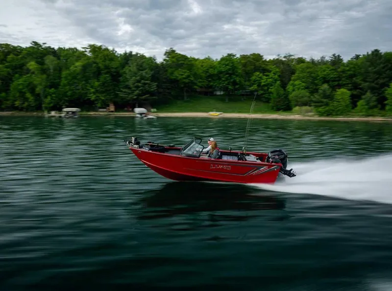 Slide: The Image of 2026 Lund 1875 Fisherman boat speeding on a lake with lush green shoreline. - 0