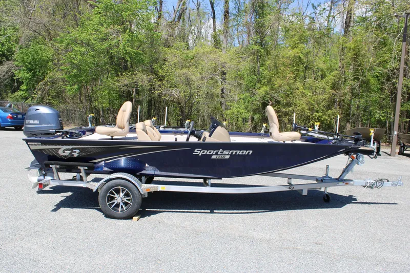 Slide: The Image of 2025 G3 Sportsman 1710 boat on trailer, parked outdoors with trees in background. - 5