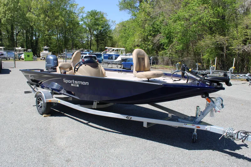 Slide: The Image of 2025 G3 Sportsman 1710 boat on trailer, parked outdoors, surrounded by trees. - 6