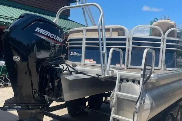 Slide: The Image of 2020 Sun Tracker Party Barge 20 DLX with Mercury outboard motor, docked under blue sky. - 2