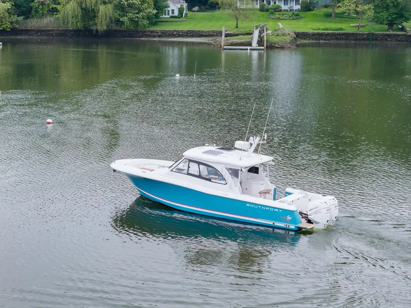 Slide: The Image of 2021 Southport 33 DC boat cruising on a calm lake with lush green surroundings. - 10