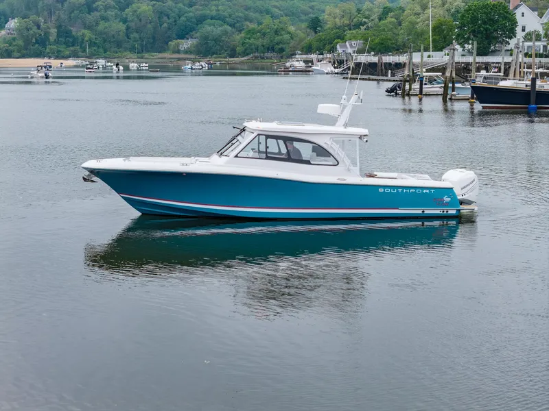 Slide: The Image of 2021 Southport 33 DC boat on calm water, surrounded by lush greenery and docks. - 13