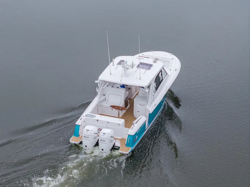 Slide: The Image of 2021 Southport 33 DC boat cruising on calm water, rear view. - 2