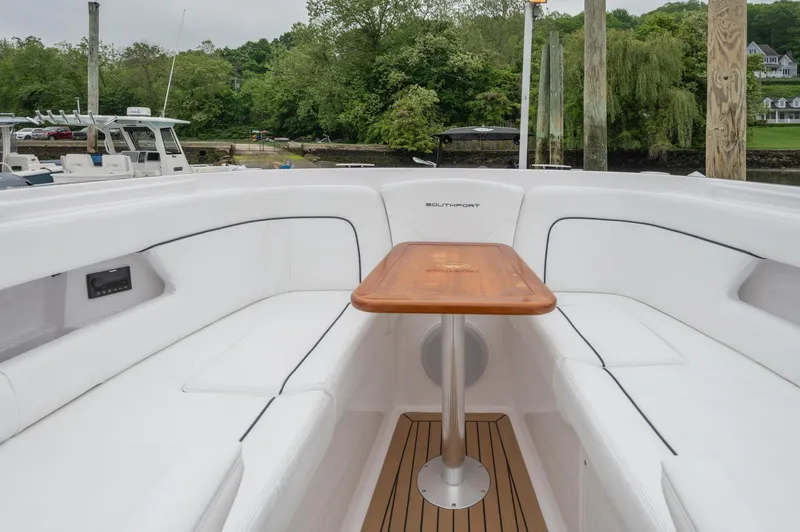 Slide: The Image of 2021 Southport 33 DC boat interior with white seating and wooden table. - 20