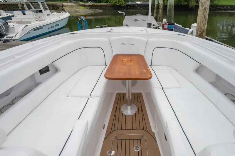 Slide: The Image of 2021 Southport 33 DC boat interior with white seating and wooden table. - 21