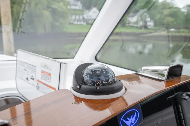 Slide: The Image of 2021 Southport 33 DC boat dashboard with compass, wooden finish, and scenic water view. - 32