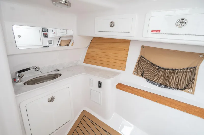 Slide: The Image of 2021 Southport 33 DC boat interior with sink, storage, and wooden accents. - 33