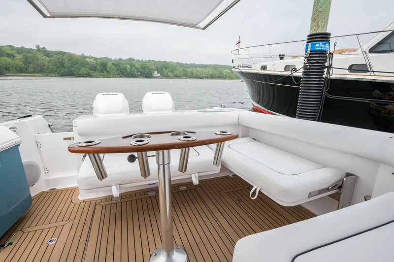 Slide: The Image of 2021 Southport 33 DC boat interior with seating and table on a serene waterfront. - 40