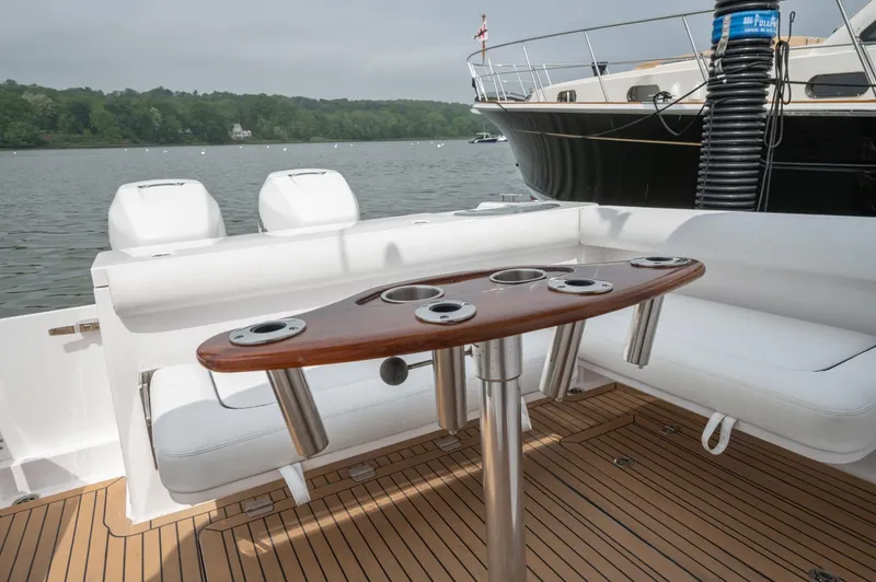 Slide: The Image of 2021 Southport 33 DC boat interior with seating and wooden table on a lake. - 45