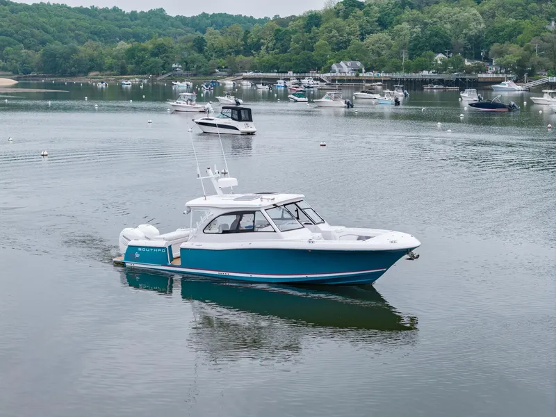 Slide: The Image of 2021 Southport 33 DC boat on a calm lake with surrounding greenery. - 6