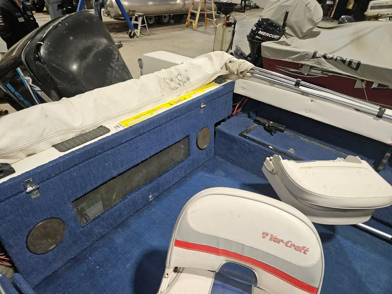 Slide: The Image of 1997 Yar-Craft 192 Michigan boat interior with blue carpet and white seats in a garage. - 6