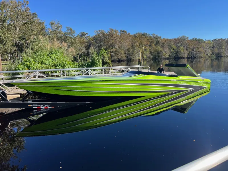 Slide: The Image of 2025 Velocity Raptor speedboat with vibrant green design on a calm river. - 3