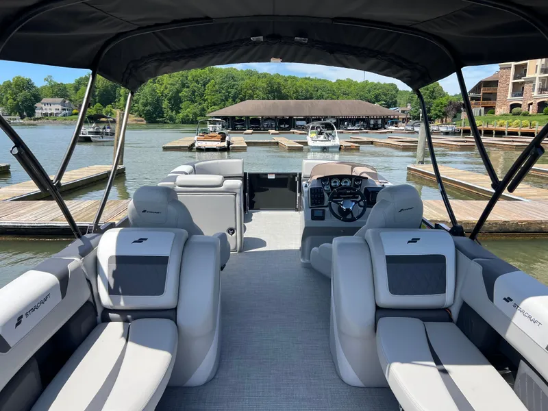 Slide: The Image of 2025 Starcraft SLS 3 pontoon boat docked at a scenic marina. - 14