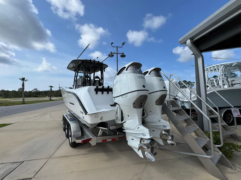 Slide: The Image of 2025 Cape Horn 32 XS boat with dual engines on a trailer, parked outdoors. - 12