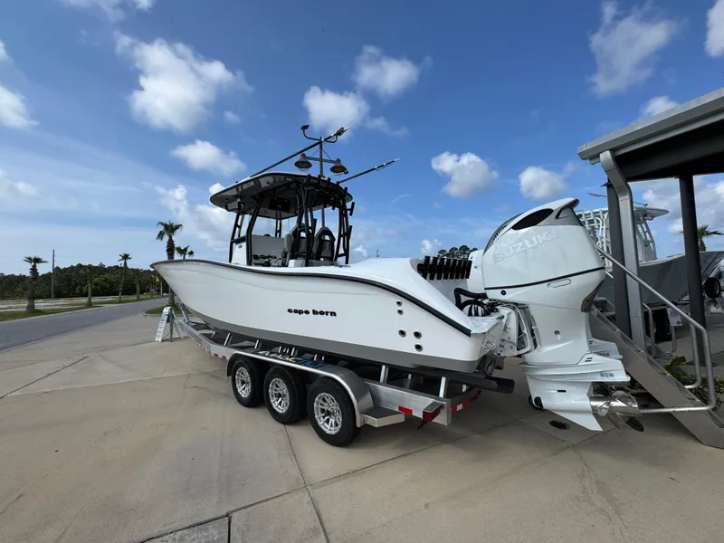 Slide: The Image of 2025 Cape Horn 32 XS boat on trailer, parked outdoors under a blue sky. - 13