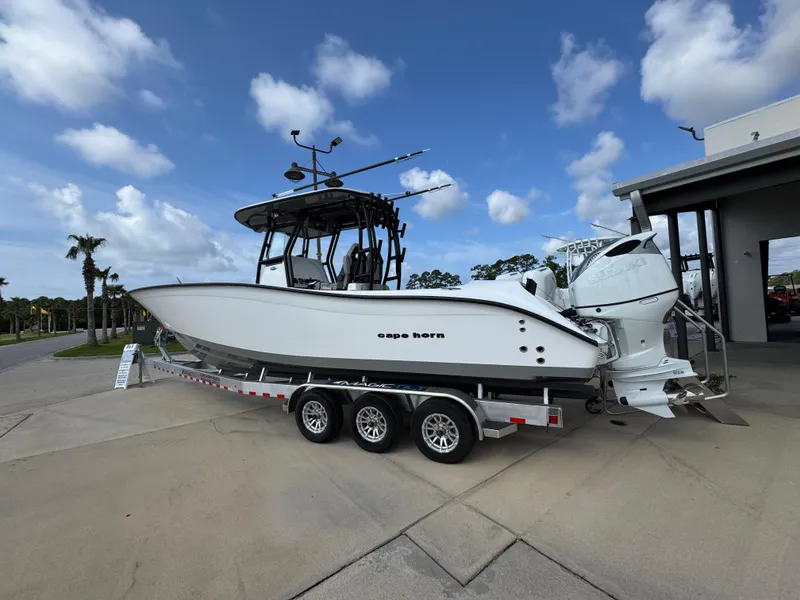 Slide: The Image of 2025 Cape Horn 32 XS boat on a trailer, parked outdoors under a partly cloudy sky. - 14
