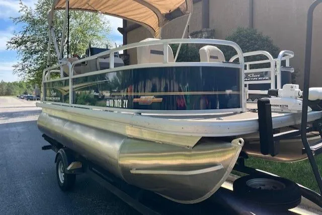 Slide: The Image of 2023 Sun Tracker Bass Buggy 16 XL Select pontoon boat on trailer, parked outdoors. - 4