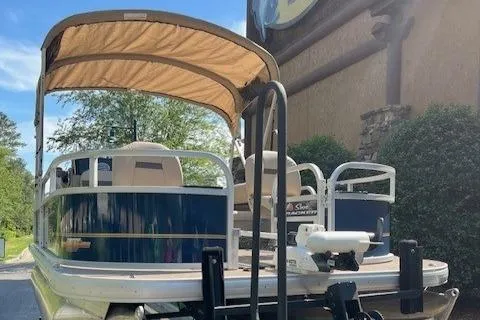 Slide: The Image of 2023 Sun Tracker Bass Buggy 16 XL Select pontoon boat with canopy, parked outdoors. - 5