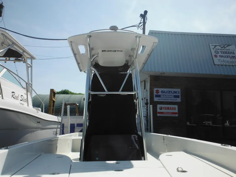 Slide: The Image of 2011 Ranger 2410 Bay Ranger boat with T-top, docked near Yamaha and Suzuki signs. - 8