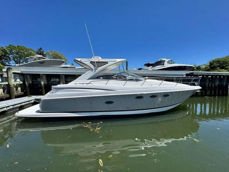 Slide: The Image of 2009 Regal Commodore 4060 yacht cruising near scenic coastal cliffs. - 2