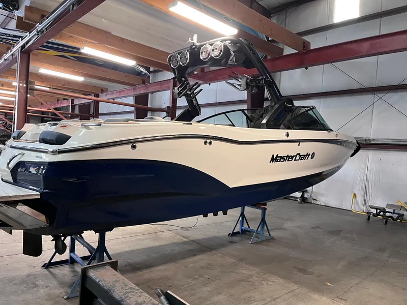 Slide: The Image of 2022 MasterCraft X26 boat in a workshop, elevated on stands. - 4