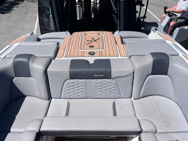 Slide: The Image of 2022 MasterCraft X26 boat interior with gray seating and wood accents. - 9