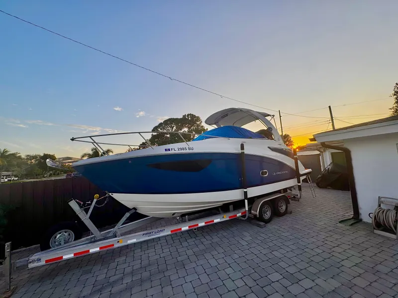 Slide: The Image of 2020 Regal 26XO boat on trailer at sunset, parked on a paved driveway. - 2