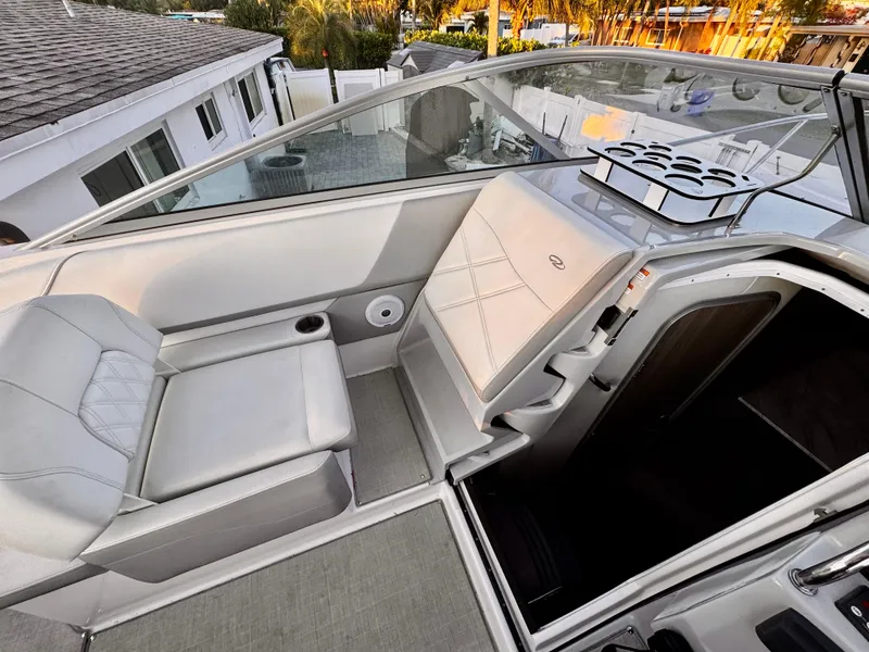 Slide: The Image of 2020 Regal 26XO boat interior with seating and cup holders, docked near a house. - 23