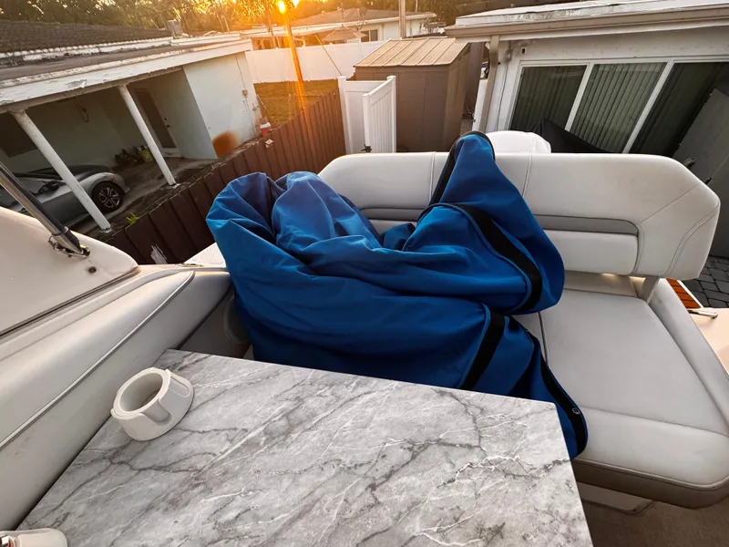 Slide: The Image of 2020 Regal 26XO boat interior with marble table and blue blanket at sunset. - 30