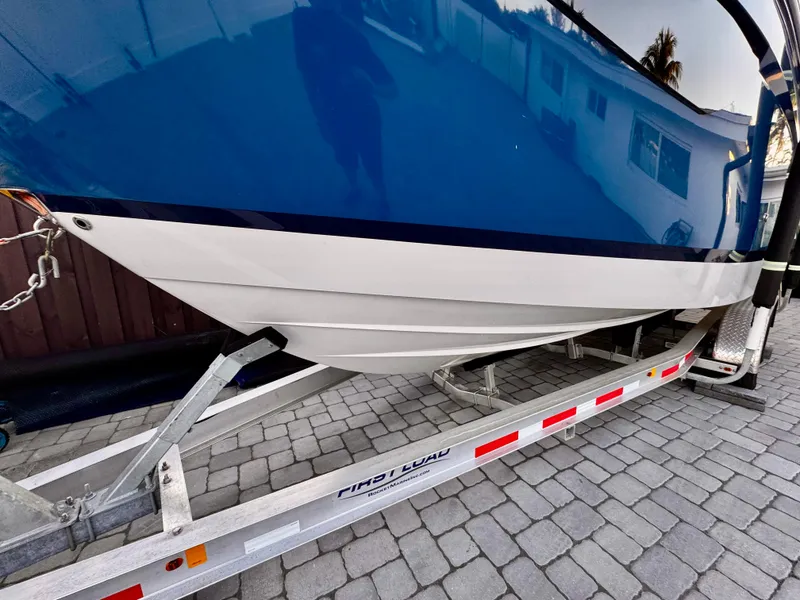 Slide: The Image of 2020 Regal 26XO boat on trailer, blue and white hull, parked on cobblestone driveway. - 5