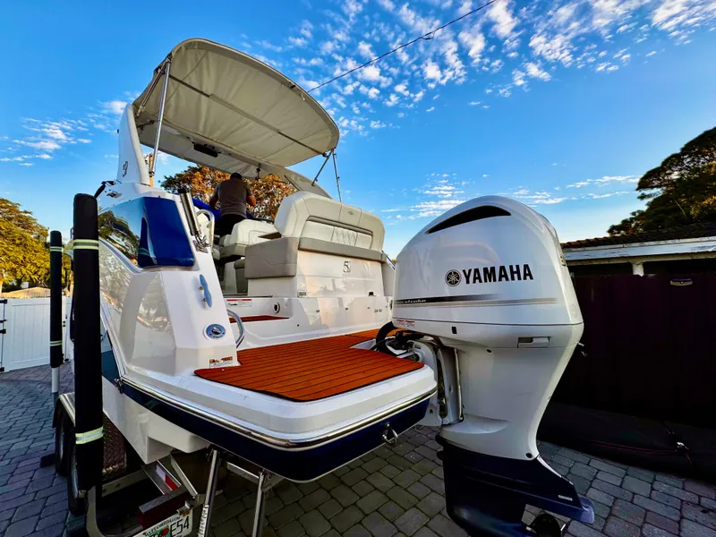Slide: The Image of 2020 Regal 26XO boat with Yamaha outboard motor, docked under a clear blue sky. - 6