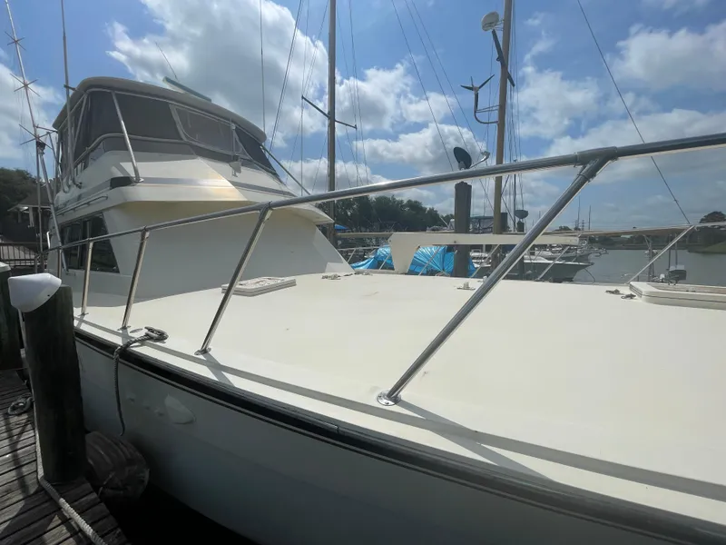 The Image of 1988 Hatteras 55 Convertible yacht docked under a partly cloudy sky. - 0