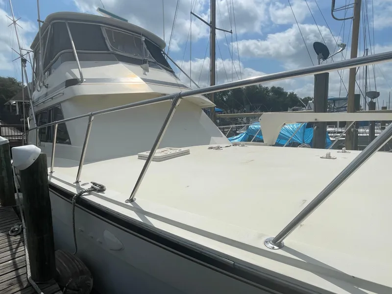 Slide: The Image of 1988 Hatteras 55 Convertible yacht docked under a partly cloudy sky. - 1