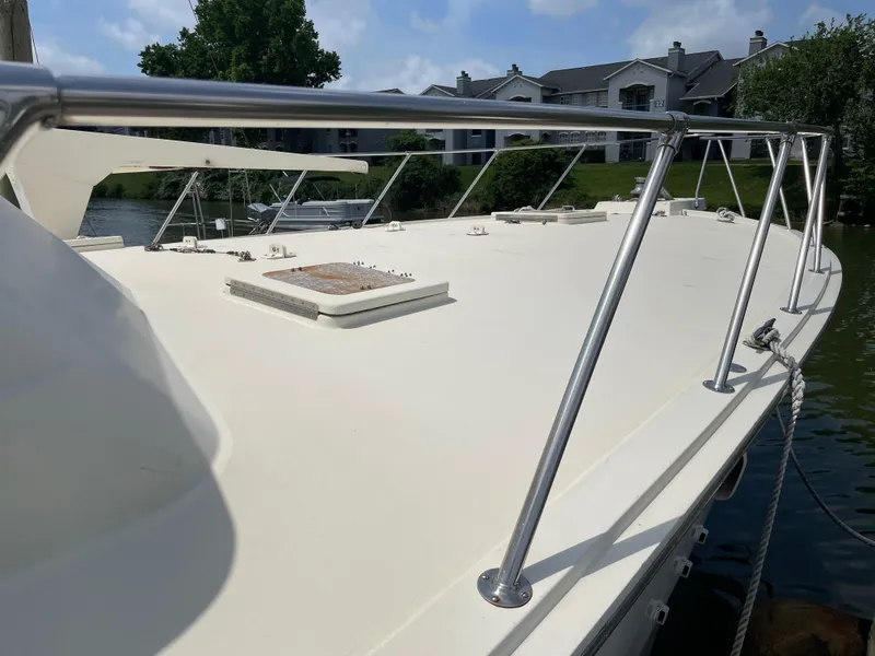 Slide: The Image of 1988 Hatteras 55 Convertible yacht deck with railing, docked near residential area. - 10