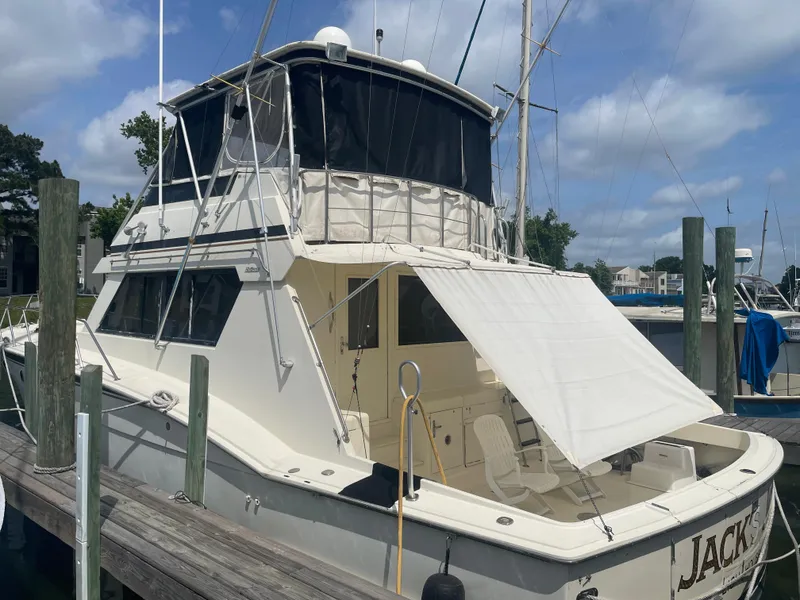 Slide: The Image of 1988 Hatteras 55 Convertible yacht docked at marina under blue sky. - 2