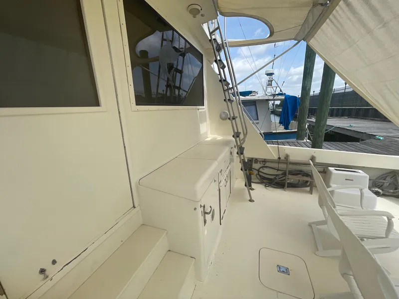 Slide: The Image of 1988 Hatteras 55 Convertible yacht deck with seating and storage, docked at marina. - 21