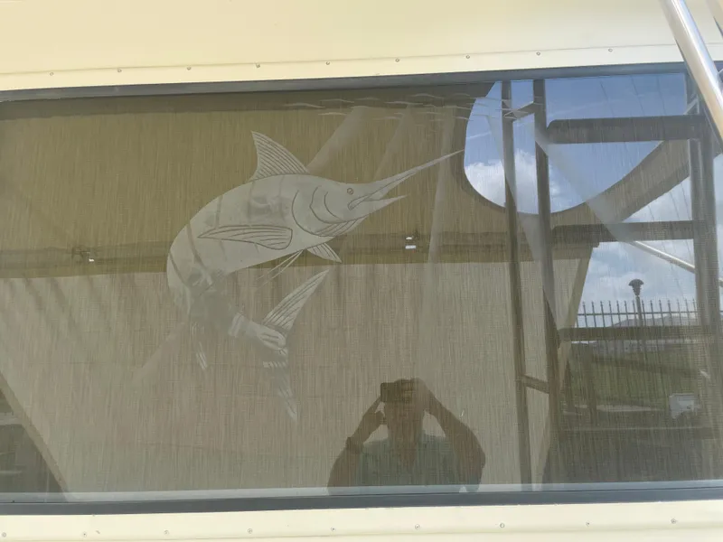 Slide: The Image of 1988 Hatteras 55 Convertible window with marlin design and reflection. - 23