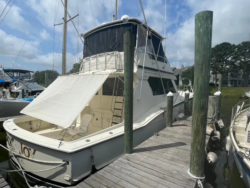 Slide: The Image of 1988 Hatteras 55 Convertible yacht docked at marina under blue sky. - 6