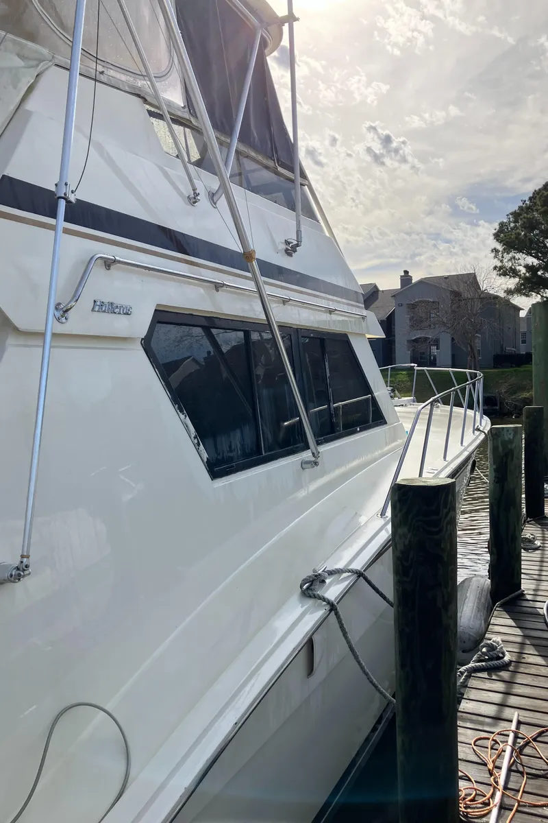 Slide: The Image of 1988 Hatteras 55 Convertible yacht docked under a cloudy sky. - 7