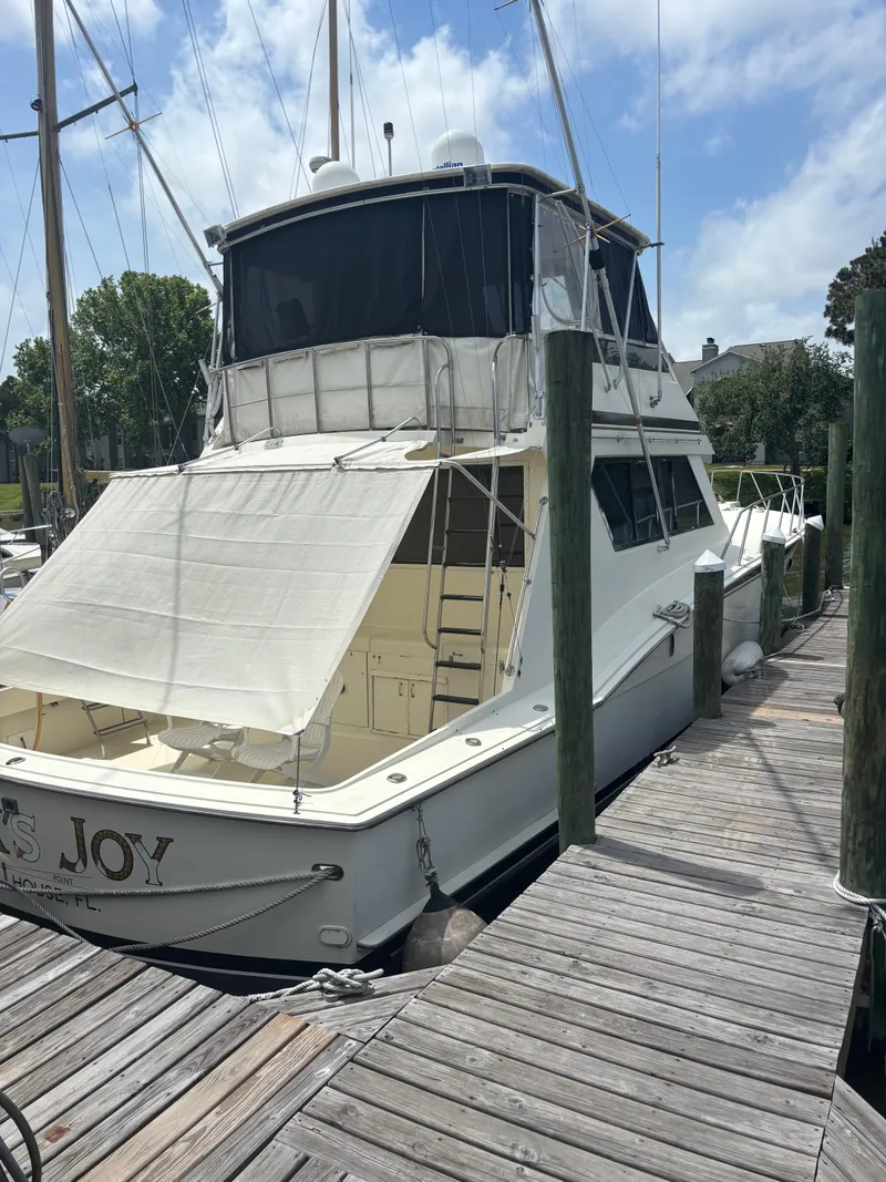 Slide: The Image of 1988 Hatteras 55 Convertible yacht docked at a marina under a clear sky. - 8