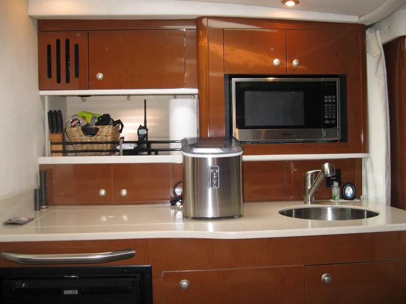 Slide: The Image of 2008 Sea Ray 330 Sundancer galley with microwave, sink, and storage cabinets. - 32