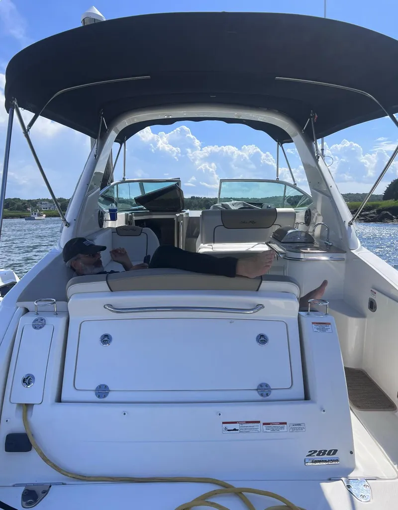 Slide: The Image of 2015 Sea Ray 280 Sundancer boat with canopy, person relaxing on deck, sunny day. - 14