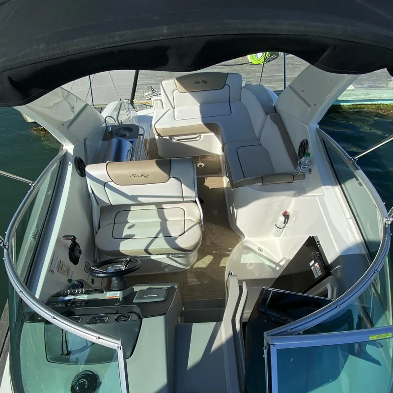 Slide: The Image of 2015 Sea Ray 280 Sundancer boat interior with seating and helm, docked on water. - 15
