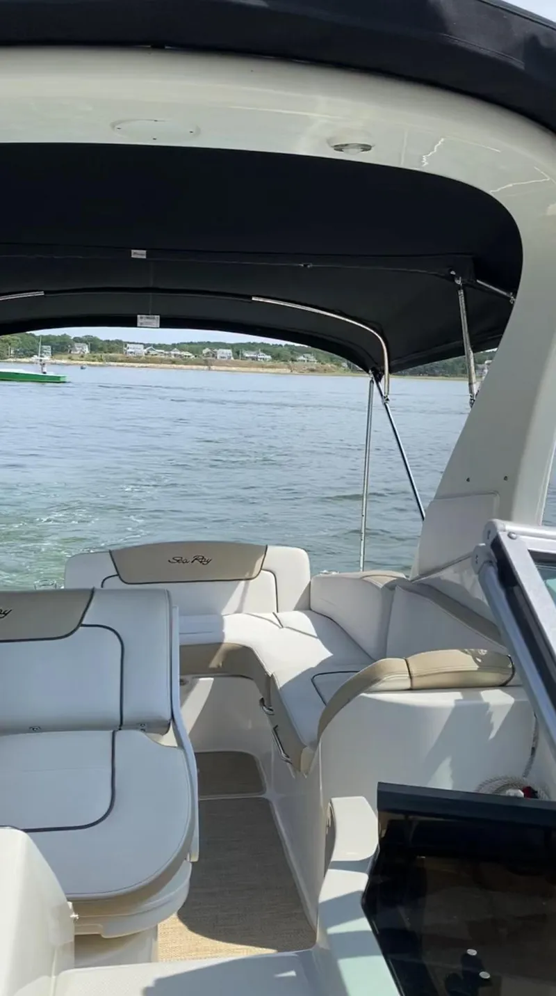 Slide: The Image of 2015 Sea Ray 280 Sundancer boat interior with seating, under canopy, on calm water. - 17