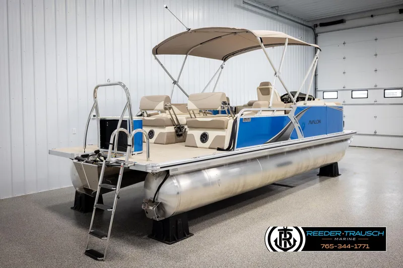 Slide: The Image of 2025 Avalon LSZ QLS pontoon boat in showroom with blue exterior and canopy. - 6