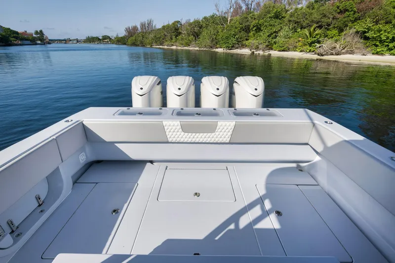 Slide: The Image of 2025 Contender 44 ST boat with quad engines, docked near a lush shoreline. - 34