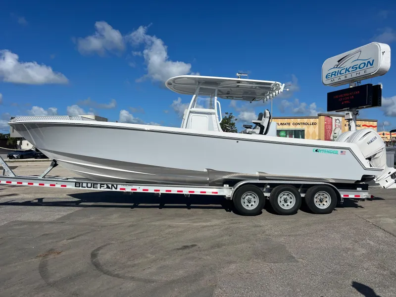 Slide: The Image of 2025 Contender 32 ST boat on trailer, parked outdoors under a clear blue sky. - 2