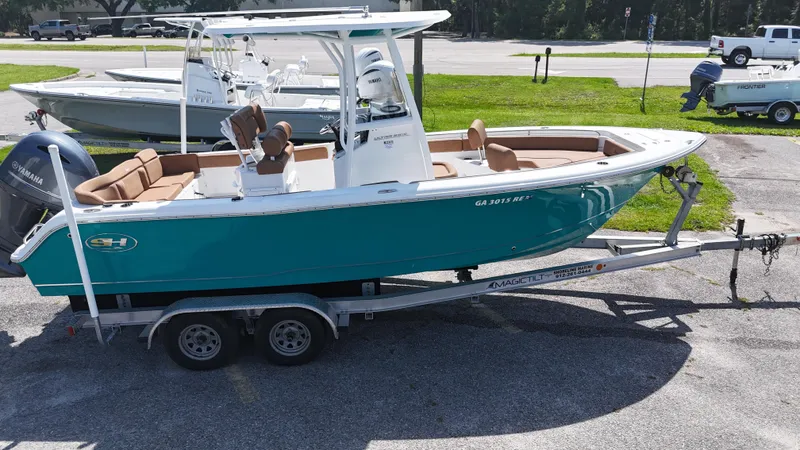Slide: The Image of 2022 Sea Hunt 229 ULTRA boat on trailer, teal hull, parked outdoors. - 1